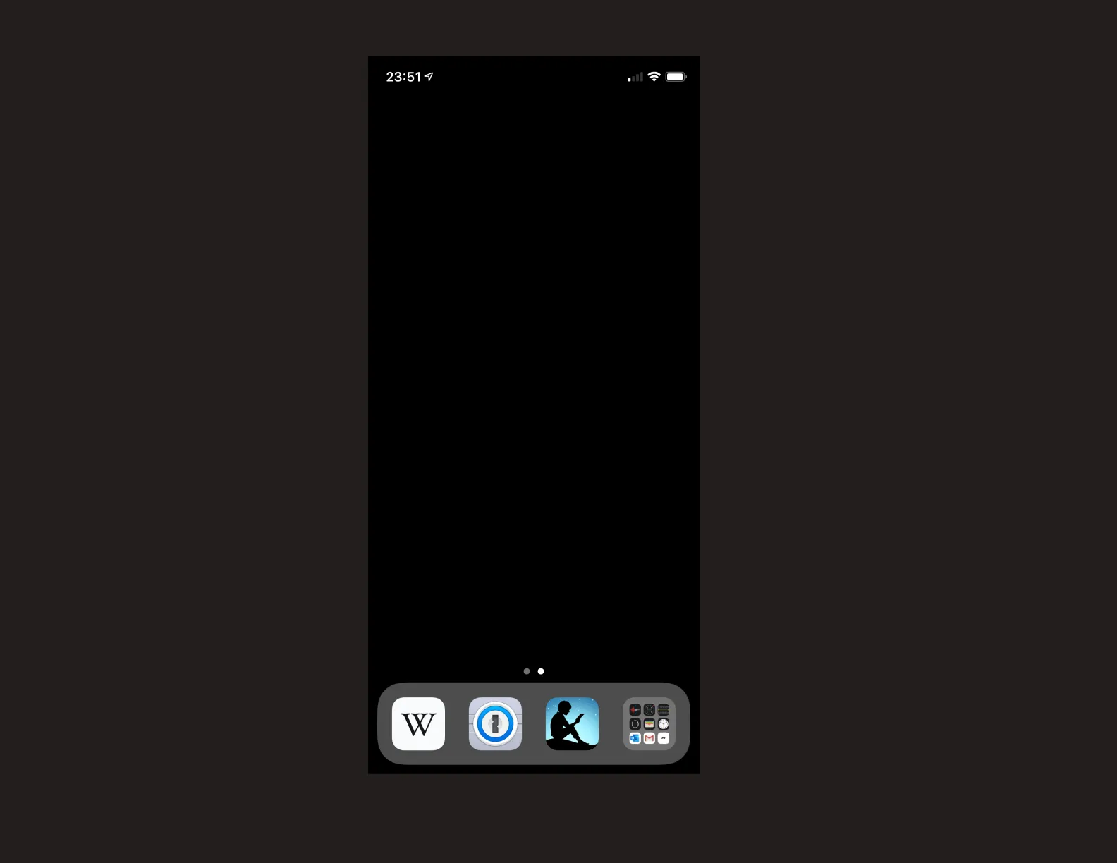 A screenshot of my iPhone&#x27;s current main screen setup. It is blank besides the bottom four app shelf items: Wikipedia, 1Password, Kindle, and a folder of all other apps. The background of the main screen is pure black.